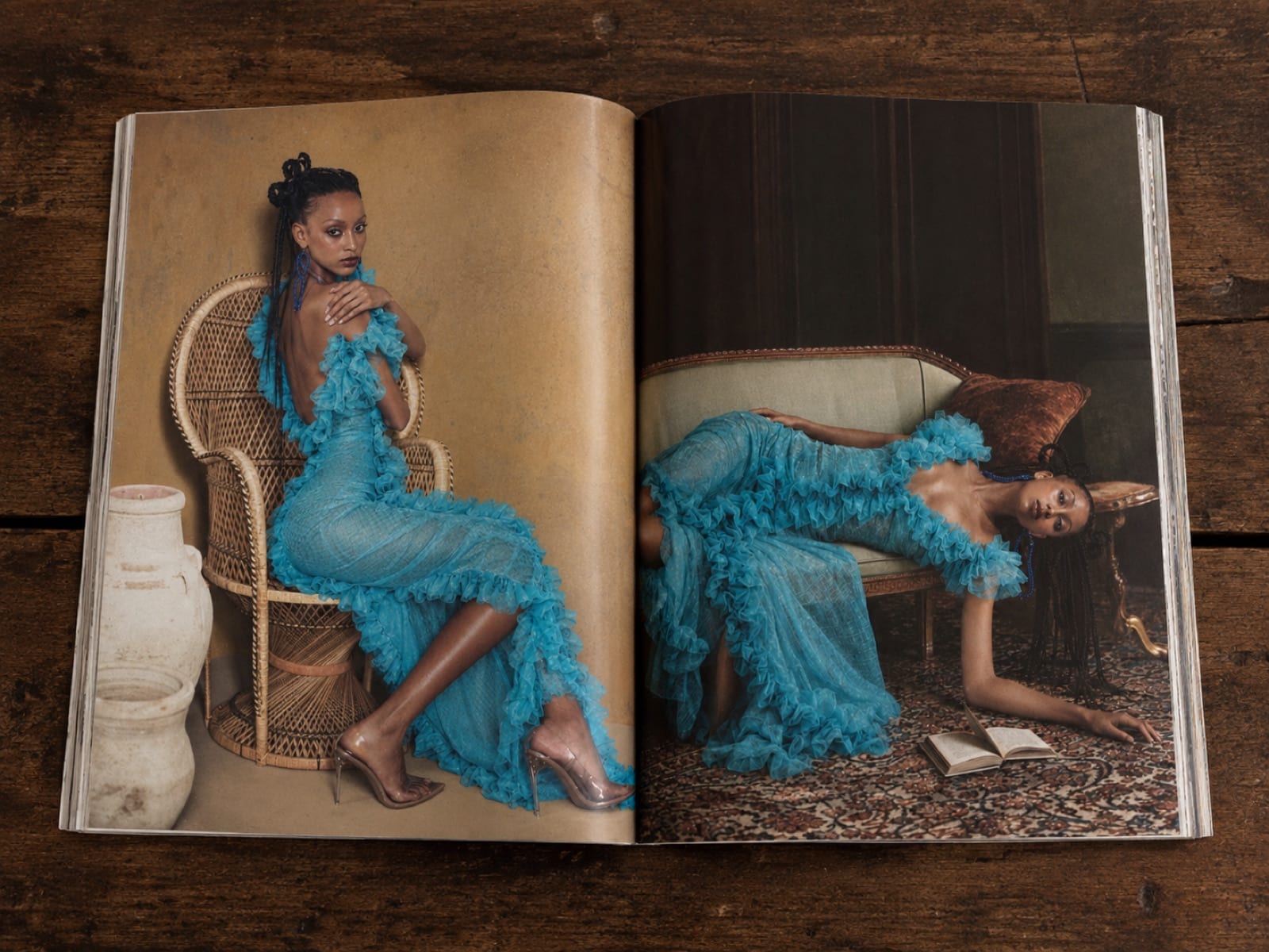 A printed spread open on a wooden table showing two portraits in the blue ruffled gown