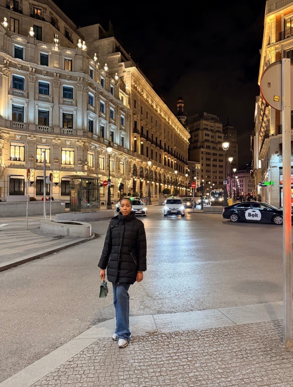 Adaeze Nwokeji standing on a cobbled street at night in front of grand illuminated buildings